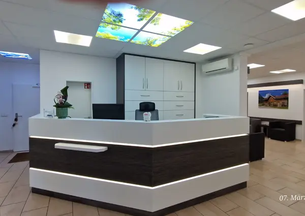 Moderne Praxis Rezeption mit Empfangstresen, Wartebereich und heller Beleuchtung.