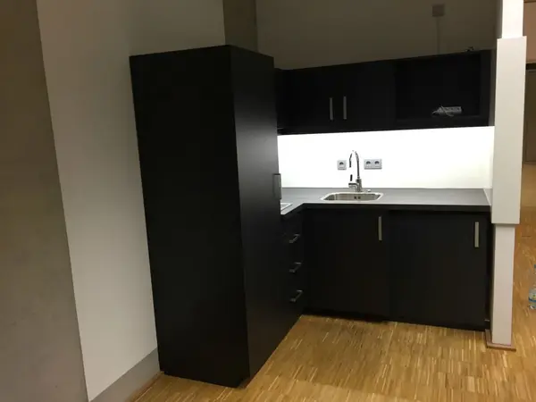 Moderne kleine Einbauküche mit dunklen Schränken, Spüle und heller Arbeitsplatte.