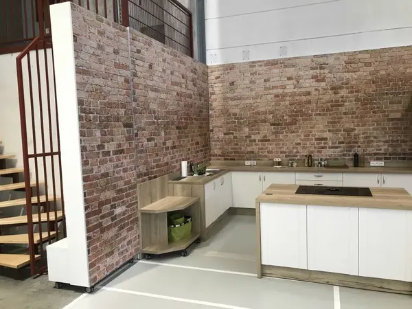 Moderne Loftküche mit Backsteinwand, Holzelementen und Kochinsel im Industrial Design.