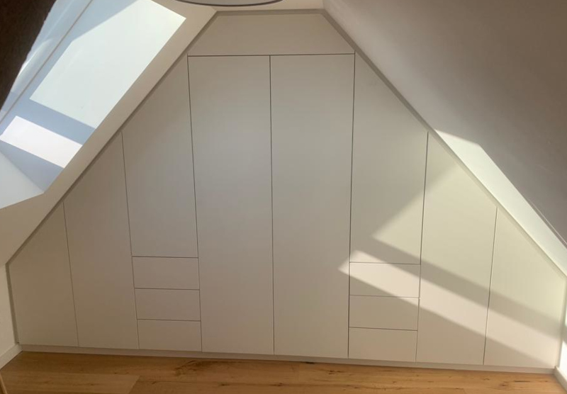 Ein maßgefertigter Einbauschrank aus Holz passt sich optimal an eine Dachschräge an.